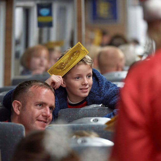 Little boy waving his Golden Ticket